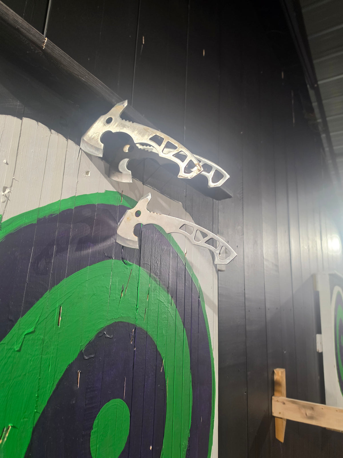 Throwing axes hanging on the target wall at Radicals Rage Rooms